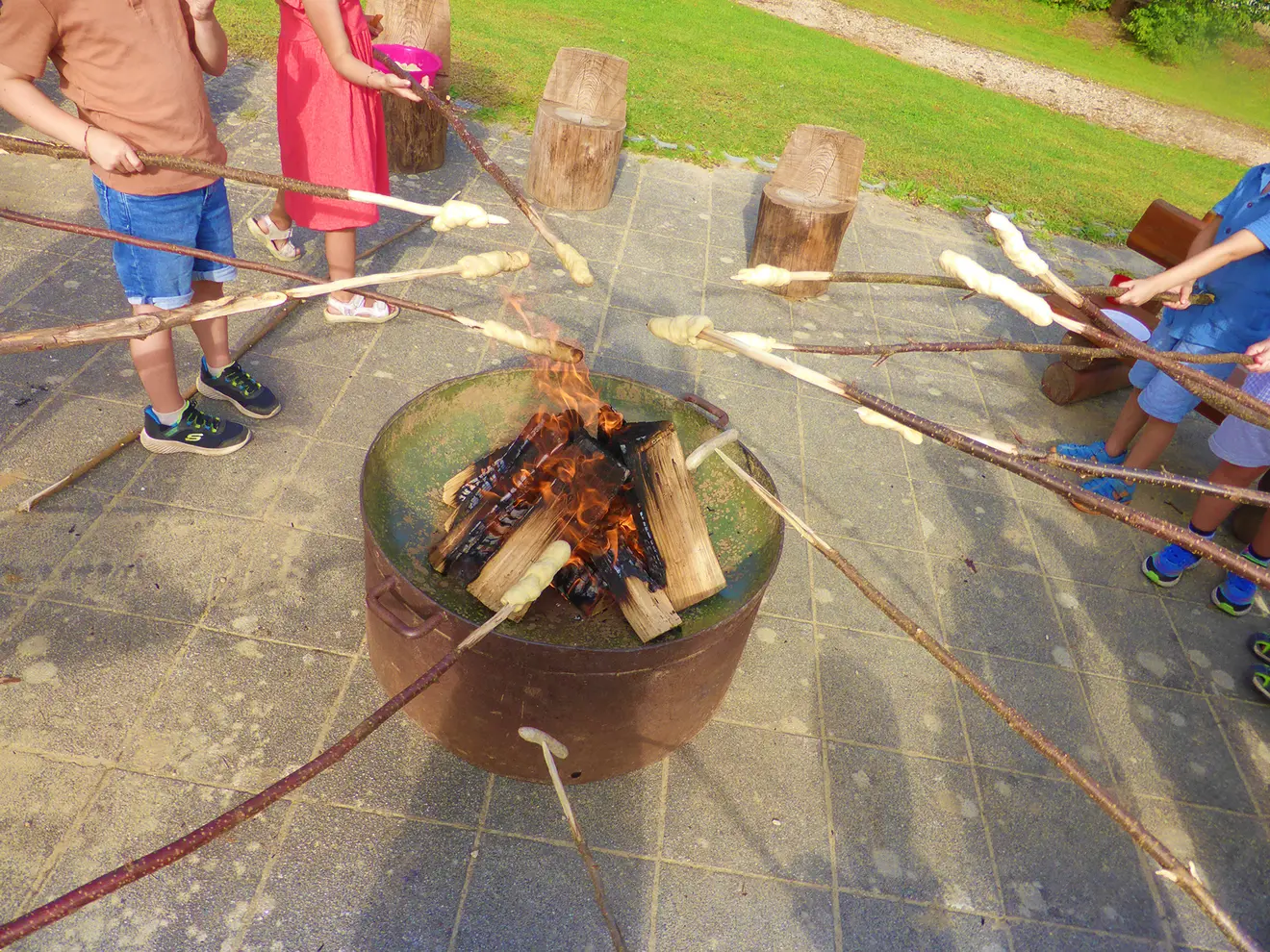Kinder rösten Stockbrot über einem offenen Feuer in einem Freizeitbereich.